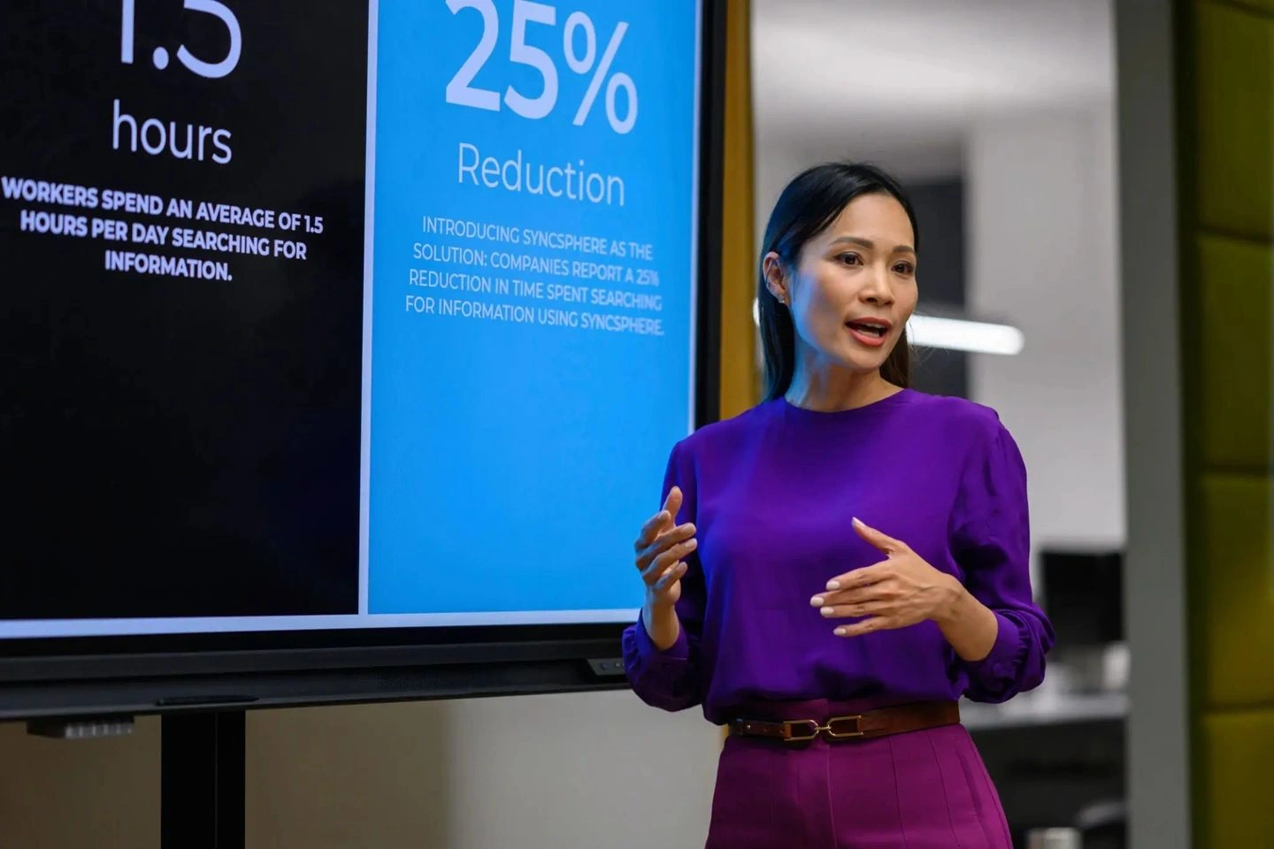 A woman presenting data on a screen showing 25% reduction.