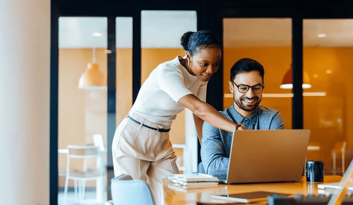 Colleagues collaborating over a laptop in a modern office.