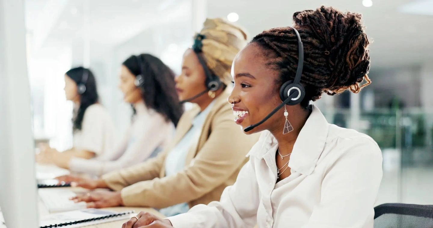 Customer service agents wearing headsets and assisting clients.