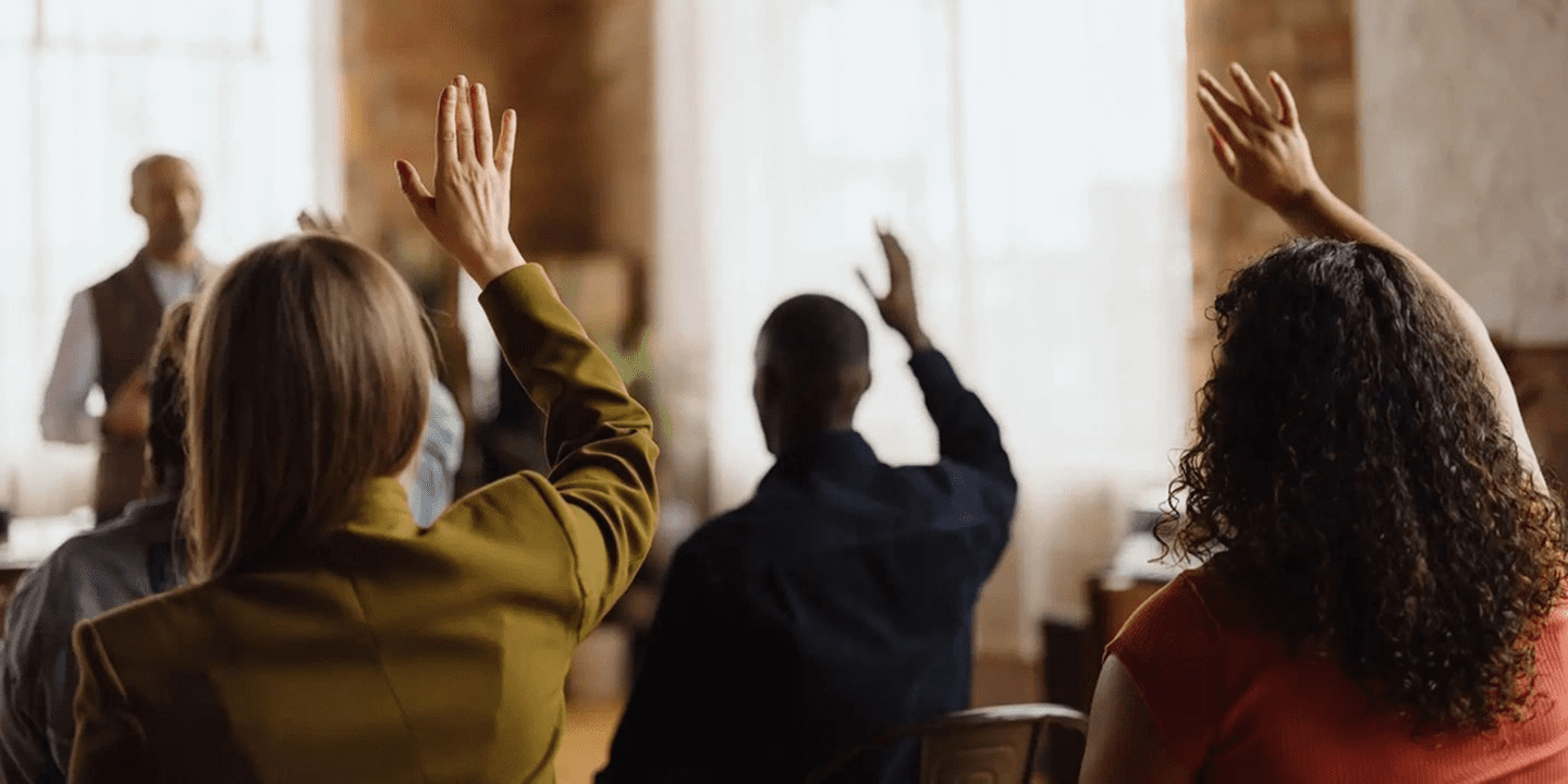 Two people raising hands in a classroom setting.